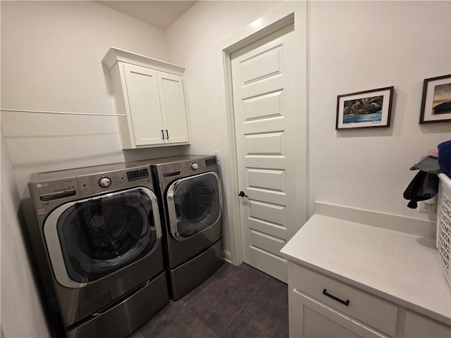 clothes washing area featuring cabinet space, washer and dryer, and dark tile patterned floors