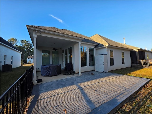 rear view of property with stucco siding, a patio, a yard, and a ceiling fan
