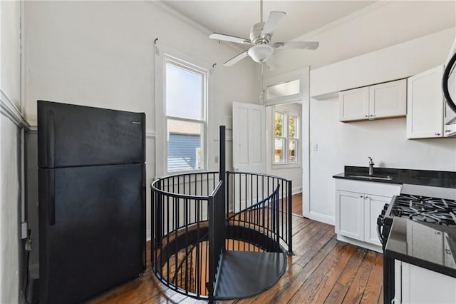 kitchen featuring a sink, white cabinets, dark wood-style floors, black appliances, and dark countertops