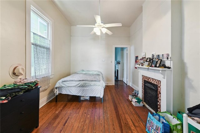 bedroom with multiple windows, baseboards, a fireplace, and wood finished floors