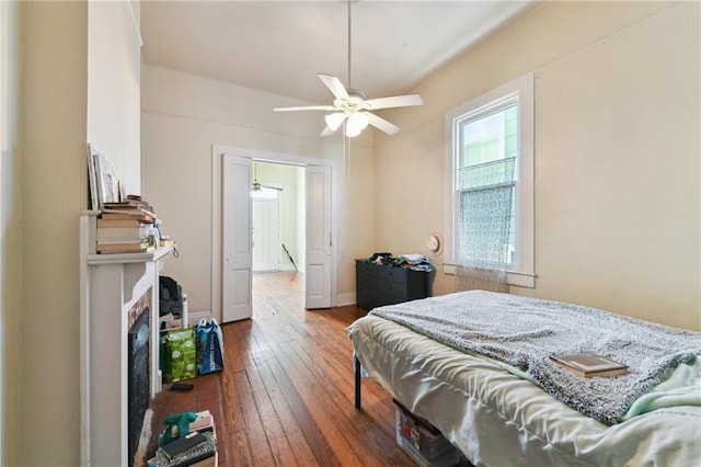 bedroom with wood-type flooring, a fireplace, and baseboards