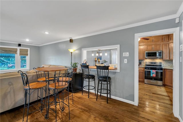 dining room with baseboards, wood finished floors, and ornamental molding