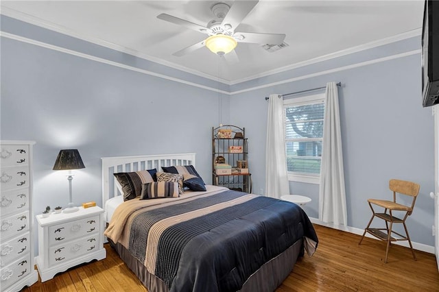 bedroom with crown molding, visible vents, a ceiling fan, baseboards, and hardwood / wood-style flooring