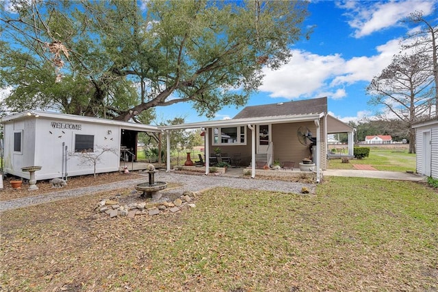 view of front facade with entry steps, driveway, a front lawn, and an attached carport