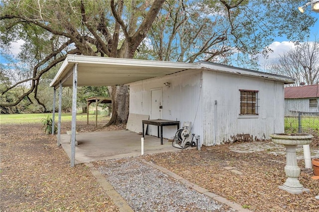 view of outdoor structure featuring driveway and an attached carport