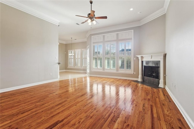 unfurnished living room featuring baseboards, a tiled fireplace, ceiling fan, wood finished floors, and crown molding