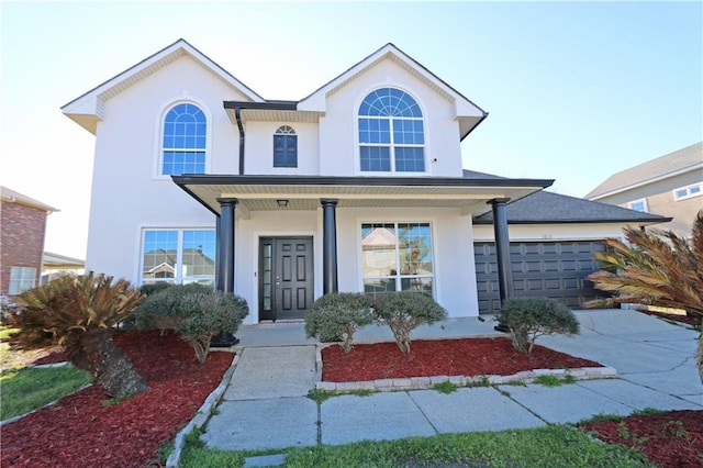 traditional-style house with a garage, concrete driveway, a porch, and stucco siding