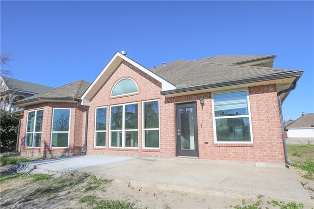 rear view of property with a patio, brick siding, and a shingled roof