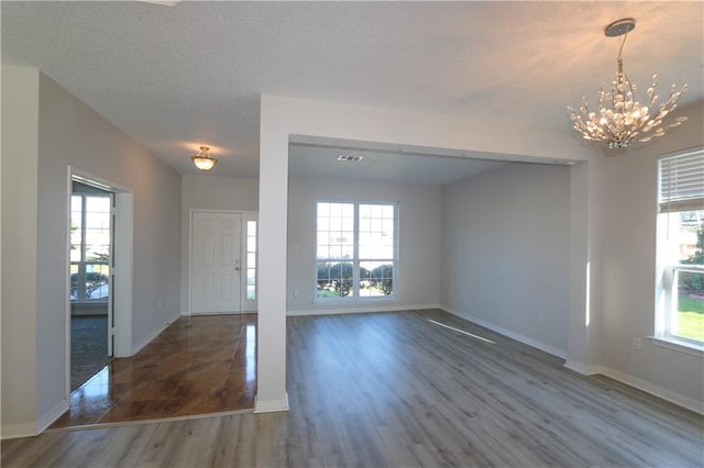 foyer featuring a wealth of natural light, an inviting chandelier, baseboards, and wood finished floors