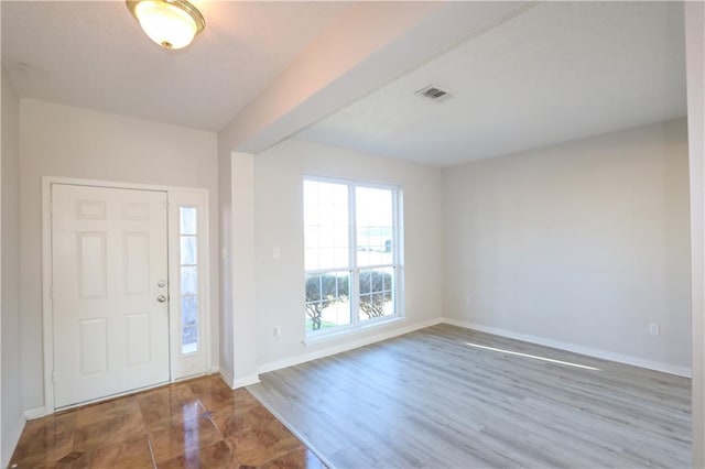 entrance foyer with wood finished floors, visible vents, and baseboards