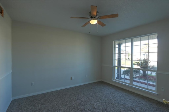 carpeted spare room featuring ceiling fan and baseboards