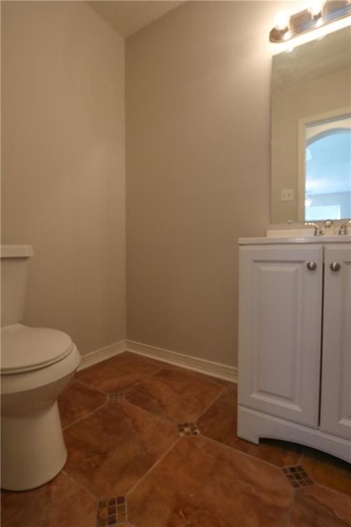 bathroom with tile patterned flooring, vanity, toilet, and baseboards