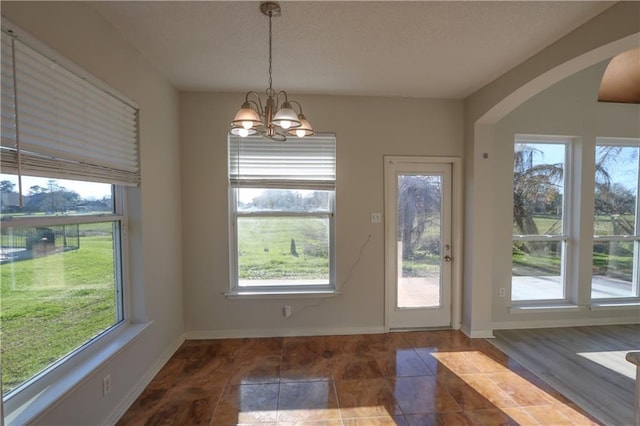 doorway to outside featuring a chandelier, a wealth of natural light, and baseboards