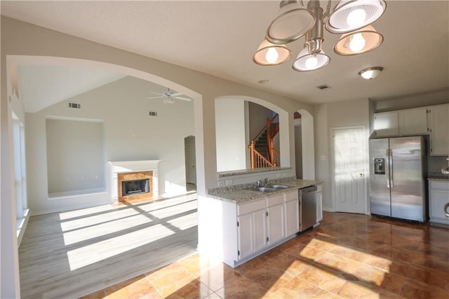 kitchen featuring visible vents, arched walkways, stainless steel appliances, and a sink