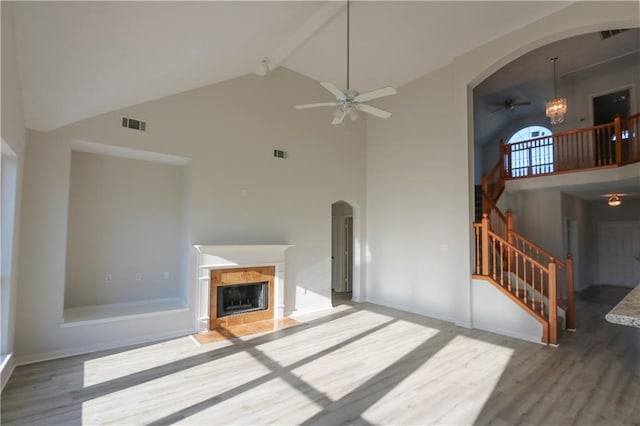 unfurnished living room with arched walkways, visible vents, a fireplace, and wood finished floors