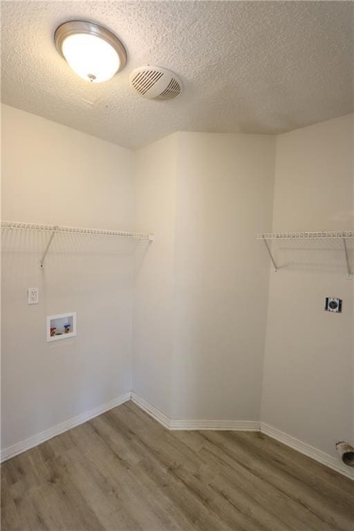 laundry area with laundry area, visible vents, wood finished floors, hookup for an electric dryer, and washer hookup