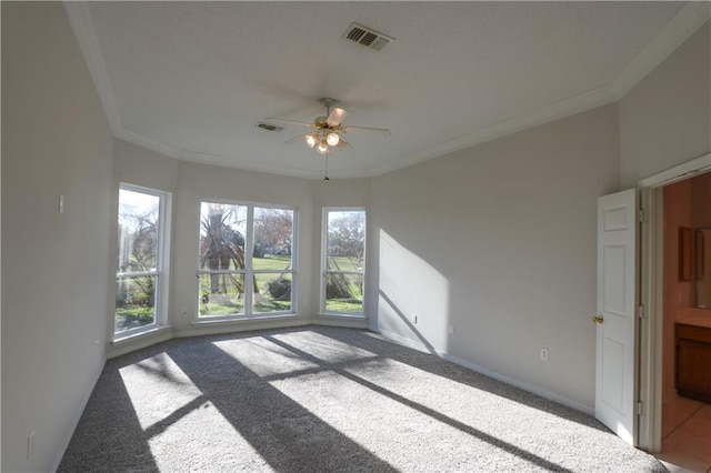 carpeted spare room with a ceiling fan, visible vents, crown molding, and baseboards