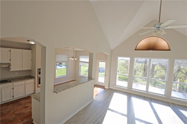 interior space featuring arched walkways, vaulted ceiling, and ceiling fan with notable chandelier