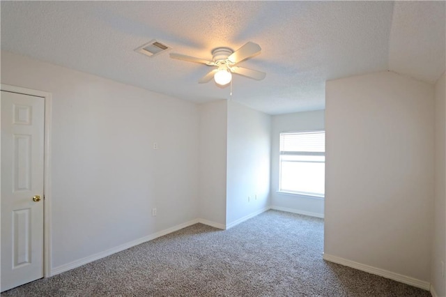 carpeted spare room featuring a textured ceiling, ceiling fan, visible vents, and baseboards