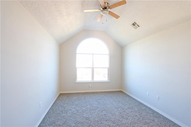 spare room featuring baseboards, visible vents, lofted ceiling, a textured ceiling, and carpet flooring