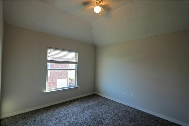 spare room with baseboards, dark carpet, vaulted ceiling, and a ceiling fan