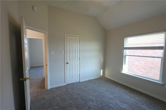 unfurnished bedroom featuring vaulted ceiling, a closet, carpet flooring, and baseboards