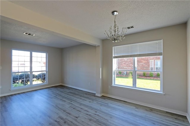 unfurnished room with a healthy amount of sunlight, visible vents, and wood finished floors