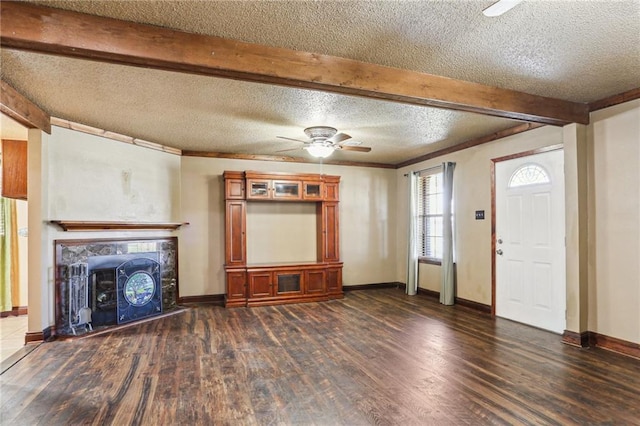 unfurnished living room with a textured ceiling, baseboards, beamed ceiling, a tiled fireplace, and dark wood finished floors