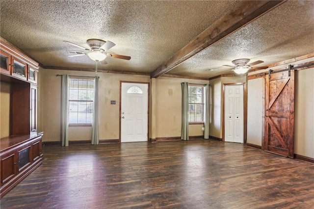 foyer entrance featuring ceiling fan, a barn door, dark wood-type flooring, baseboards, and beamed ceiling