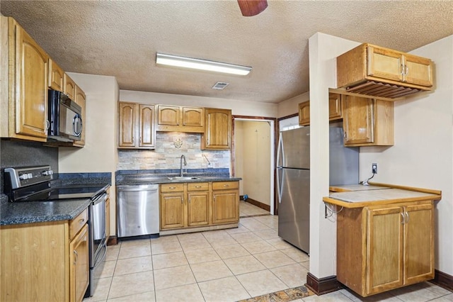 kitchen with dark countertops, visible vents, decorative backsplash, appliances with stainless steel finishes, and a sink