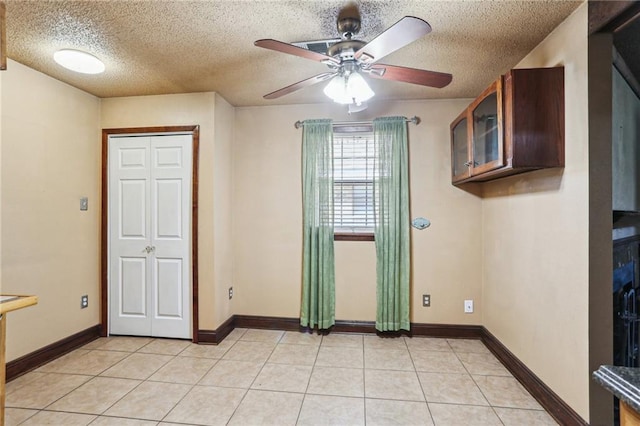 unfurnished room featuring light tile patterned floors, a ceiling fan, and baseboards