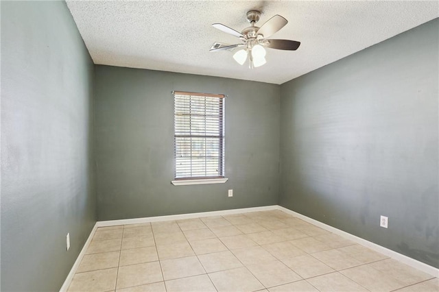 tiled empty room featuring ceiling fan, baseboards, and a textured ceiling