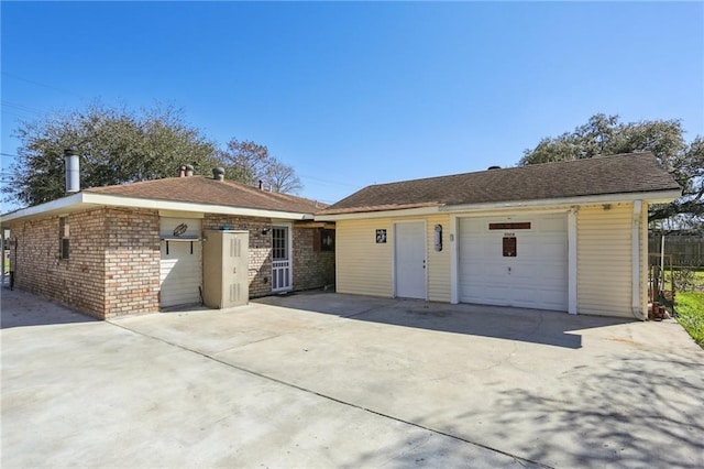 ranch-style house featuring a garage, brick siding, concrete driveway, and an outbuilding