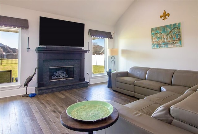 living room with baseboards, vaulted ceiling, wood finished floors, and a glass covered fireplace