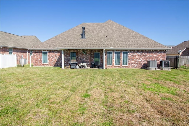 back of property with central AC unit, a lawn, a fenced backyard, and brick siding