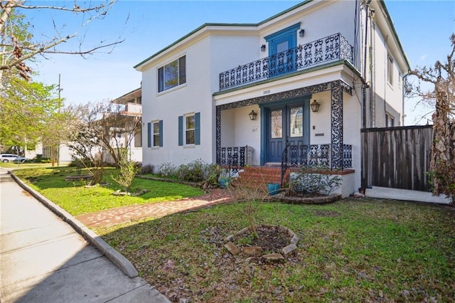 view of front of property with a balcony, covered porch, and a front yard