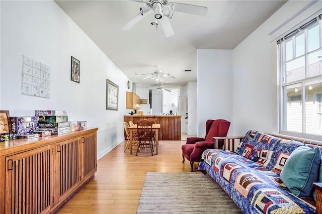 living area with ceiling fan, light wood-type flooring, and baseboards