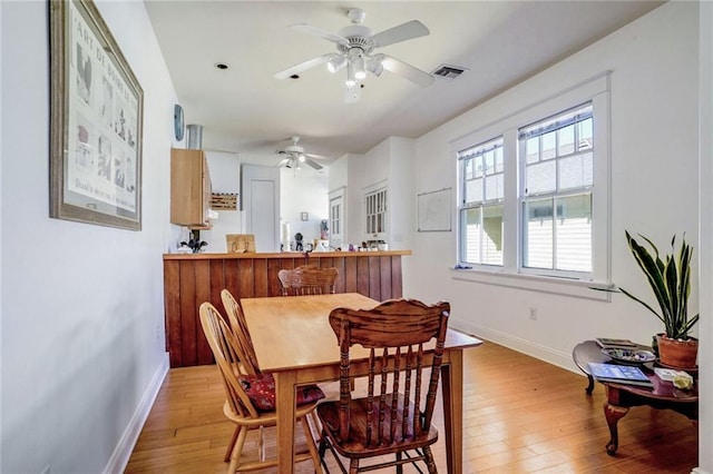 dining area with light wood-type flooring, visible vents, and baseboards