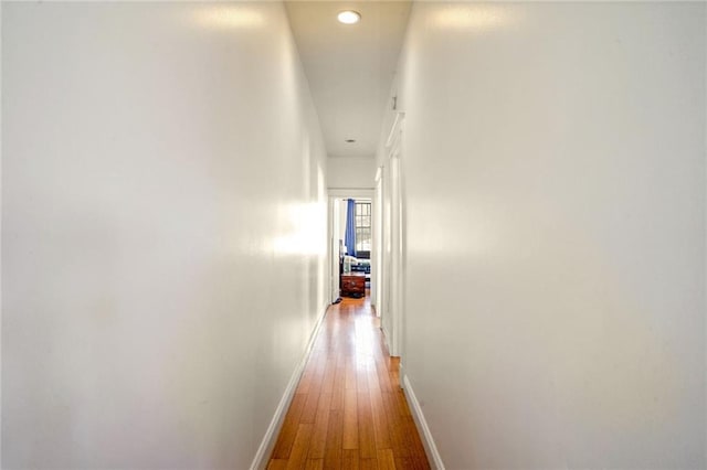 hall featuring recessed lighting, wood-type flooring, and baseboards