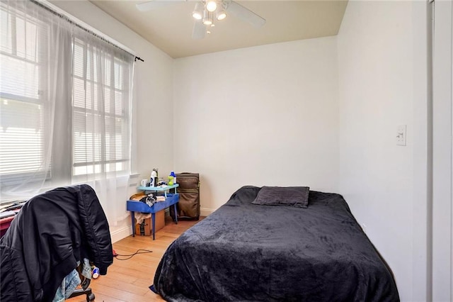 bedroom with baseboards, light wood-style flooring, and a ceiling fan