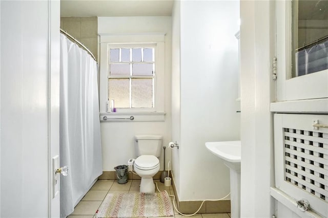 bathroom featuring a shower with curtain, baseboards, toilet, and tile patterned floors