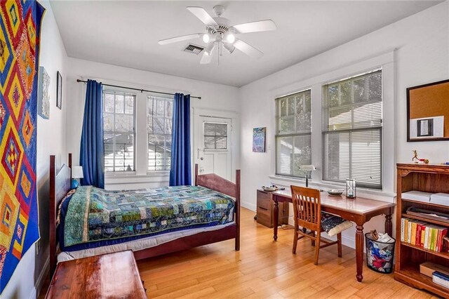 bedroom with baseboards, visible vents, and wood finished floors