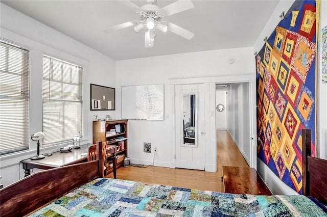 bedroom with ceiling fan, wood finished floors, and baseboards