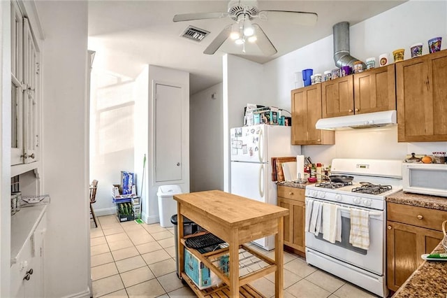 kitchen featuring white appliances, visible vents, brown cabinetry, under cabinet range hood, and light tile patterned flooring