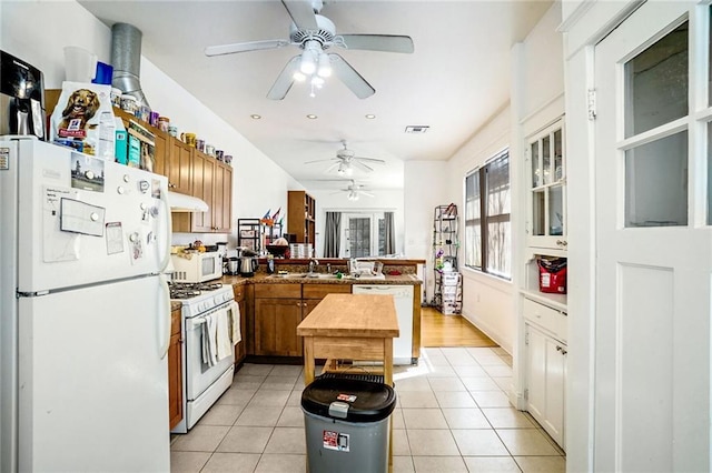 kitchen with white appliances, light tile patterned floors, visible vents, a peninsula, and a sink