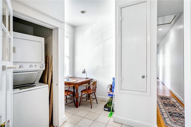 laundry room featuring laundry area, baseboards, stacked washer / dryer, and light tile patterned flooring