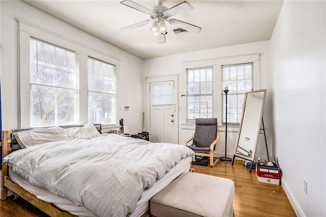 bedroom with visible vents, ceiling fan, baseboards, and wood finished floors