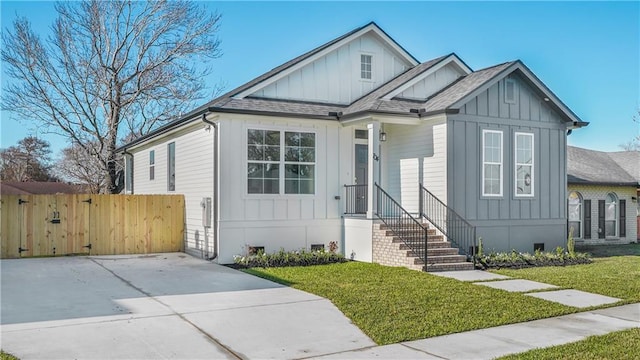 view of front facade featuring board and batten siding, fence, and a front lawn