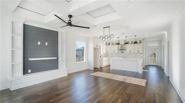 unfurnished living room with crown molding, coffered ceiling, dark wood finished floors, and ceiling fan