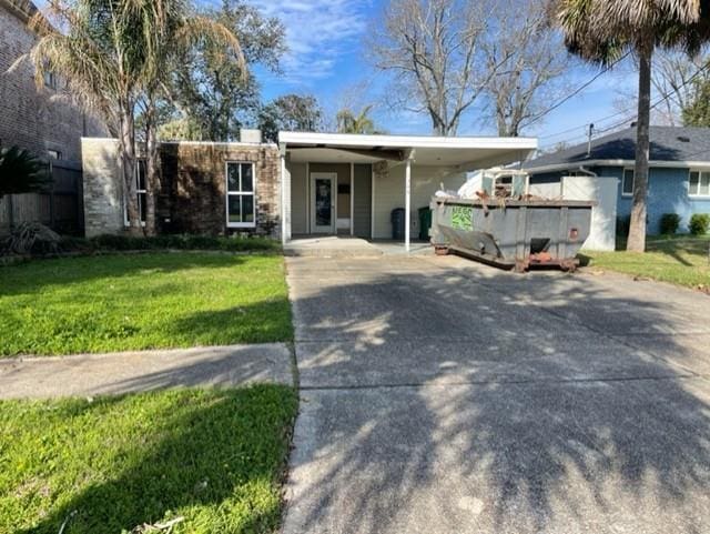 ranch-style home with a carport, stone siding, a front lawn, and concrete driveway